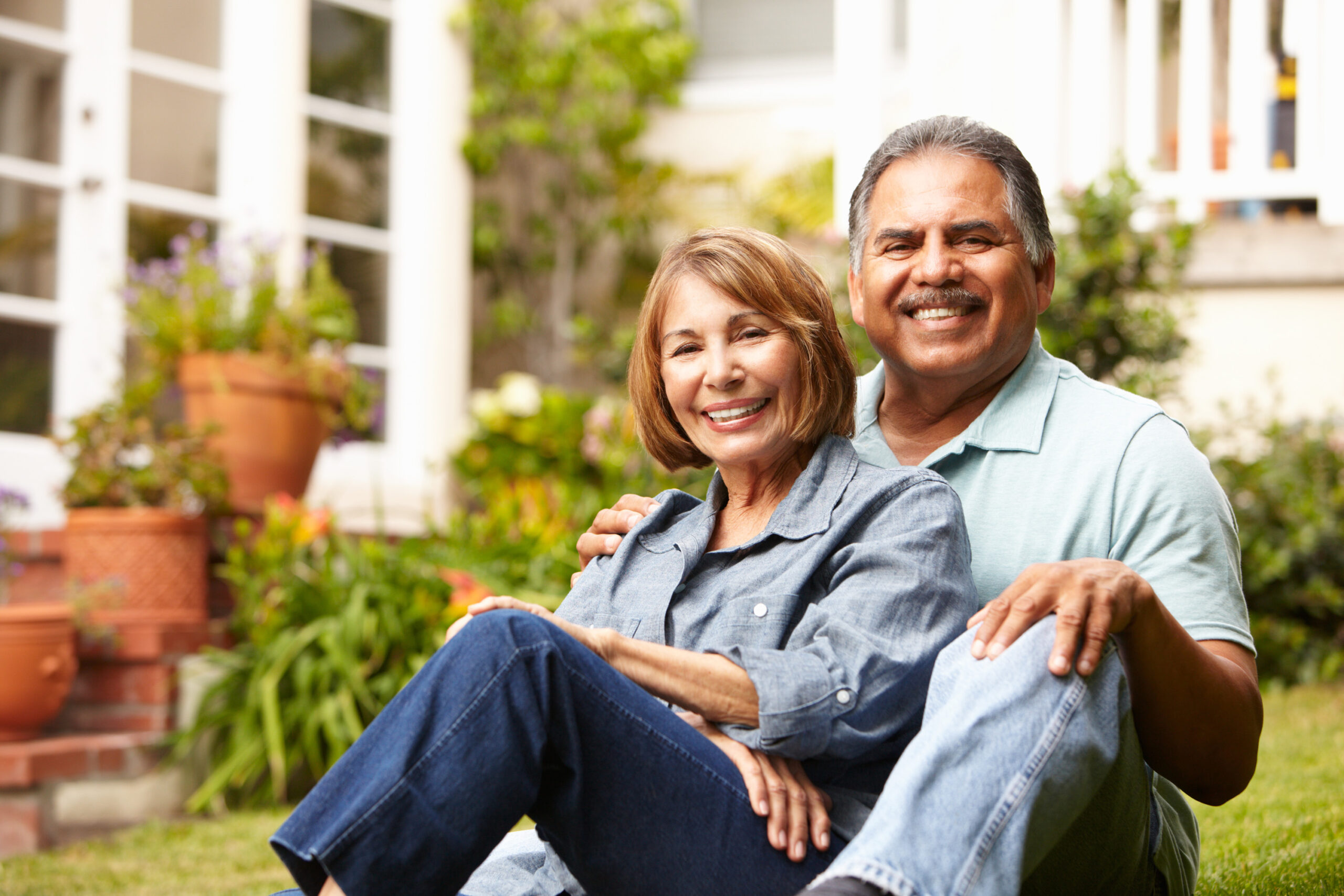 Happy senior couple sitting in front yard